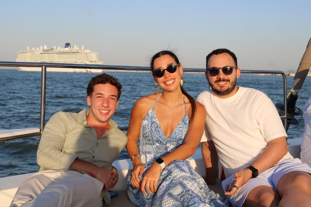 Três concierges de hotéis de luxo desfrutam de um momento descontraído a bordo, durante o evento exclusivo da Lisbon Sight Sailing no Rio Tejo